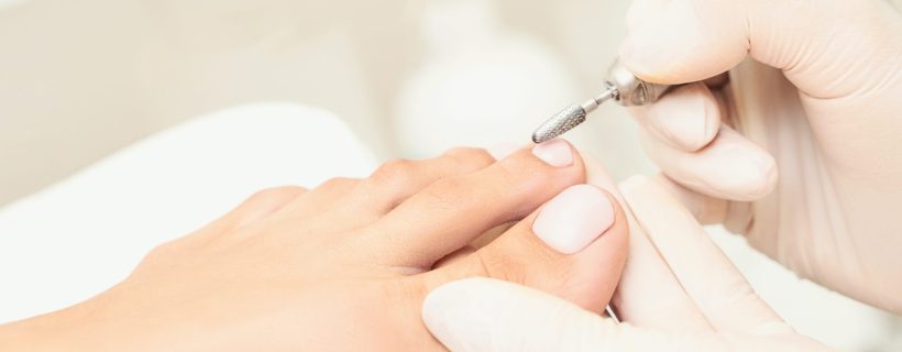 Beautiful salon procedure with pink pedicure on towel background. For decoration design. Healthcare. Woman body care. Spa treatment. White background. Nail machine polish. Medical