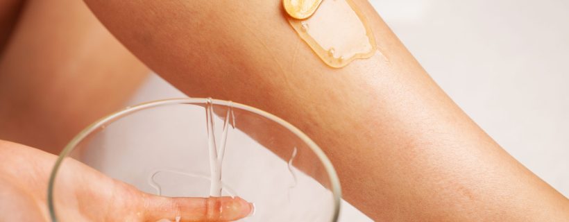 Woman holding a bowl of wax for depilation and skin care.